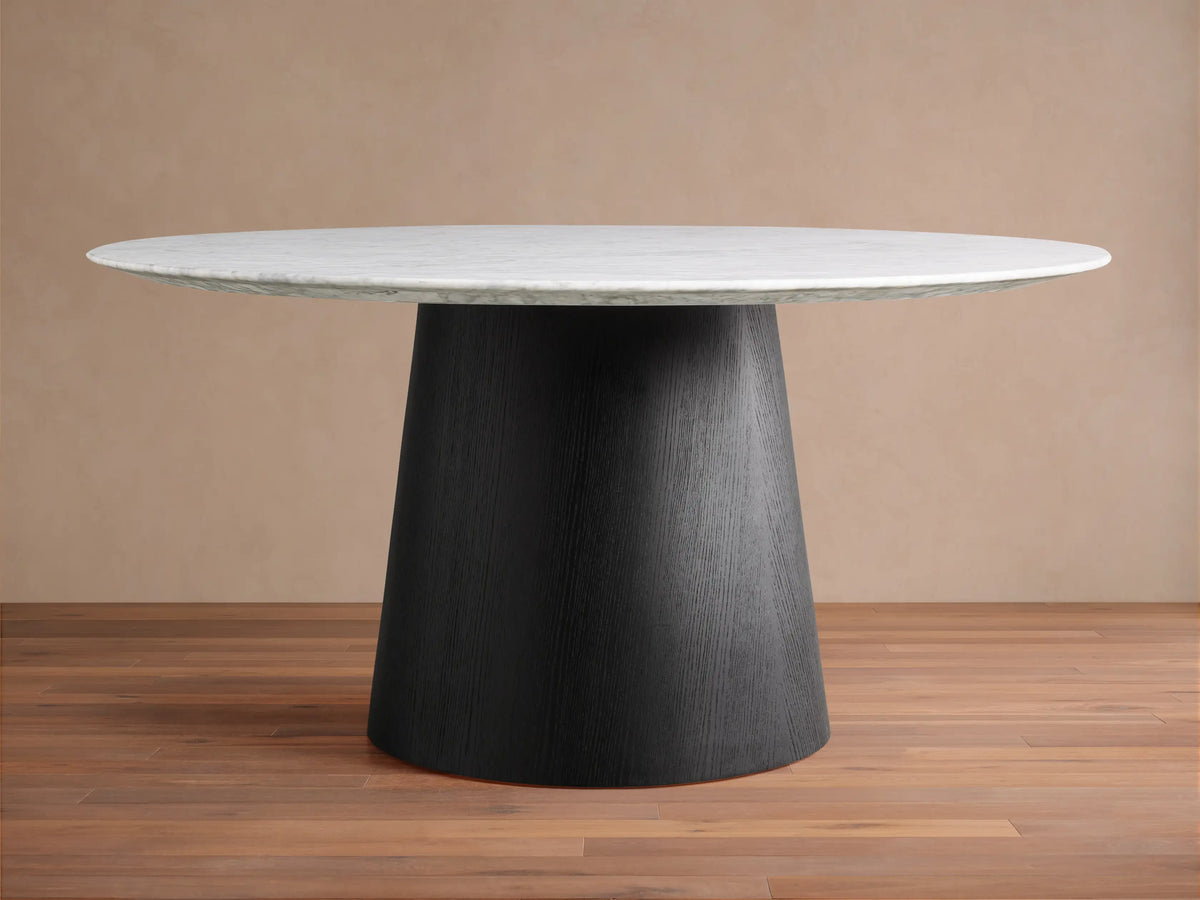 Round stone tabletop in Carrara marble, showing grey veining patterns on a smooth surface, viewed from above against a beige background.
