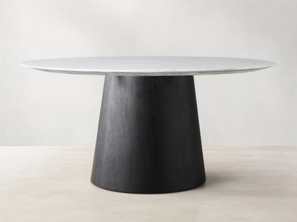Round dining table with a Carrara marble top in white, featuring subtle veining. The base is a black, cone-shaped structure made of plywood and oak veneers.
