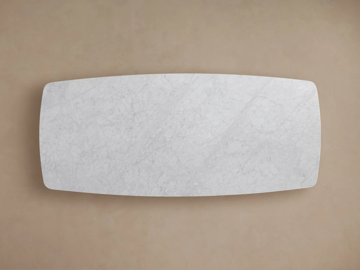 Close-up of Saint Germain Stone Dining Table's white Carrara marble top, showing grey veining and a smooth, rounded edge.