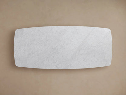 Close-up of the Saint Germain Stone Dining Table's white Carrara marble top with subtle grey veining and a curved edge.
