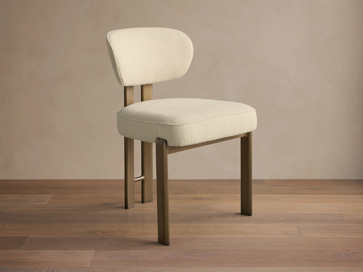 Front-quarter view of the cream Cea Dining Side Chair with antique brass frame and legs.