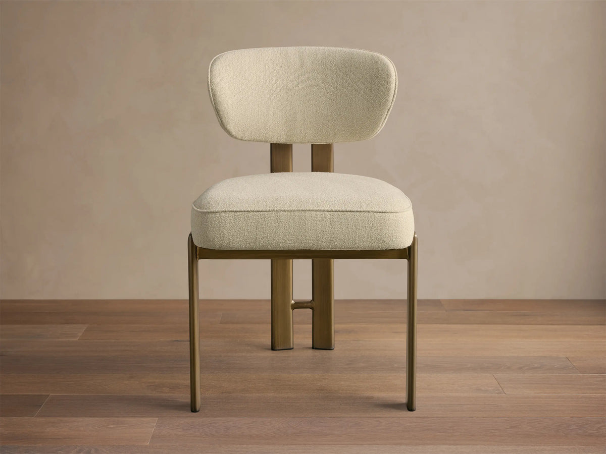 Front-quarter view of the cream Cea Dining Side Chair with antique brass frame and legs.