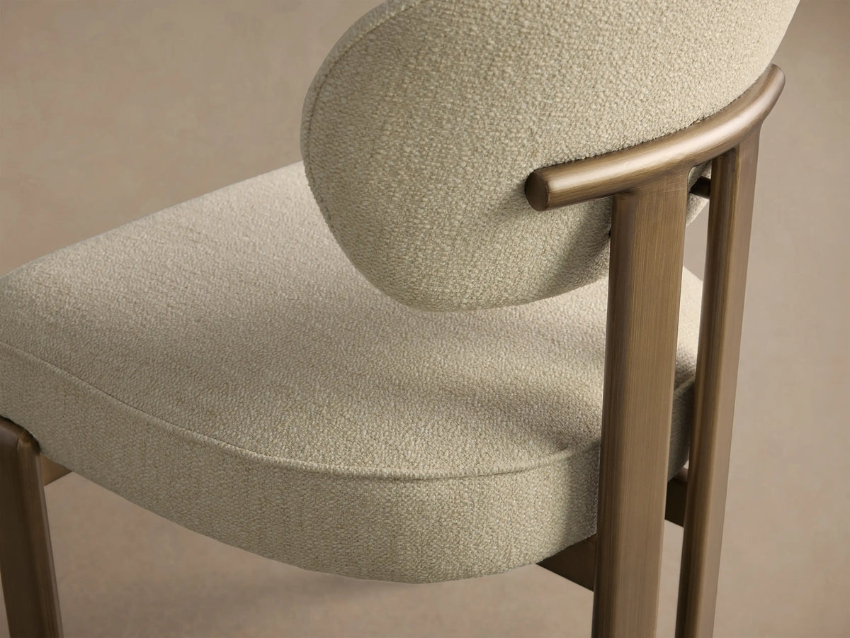 Front view of the Cea Dining Side Chair featuring a light cream upholstered seat and back, with an antique brass metal frame.