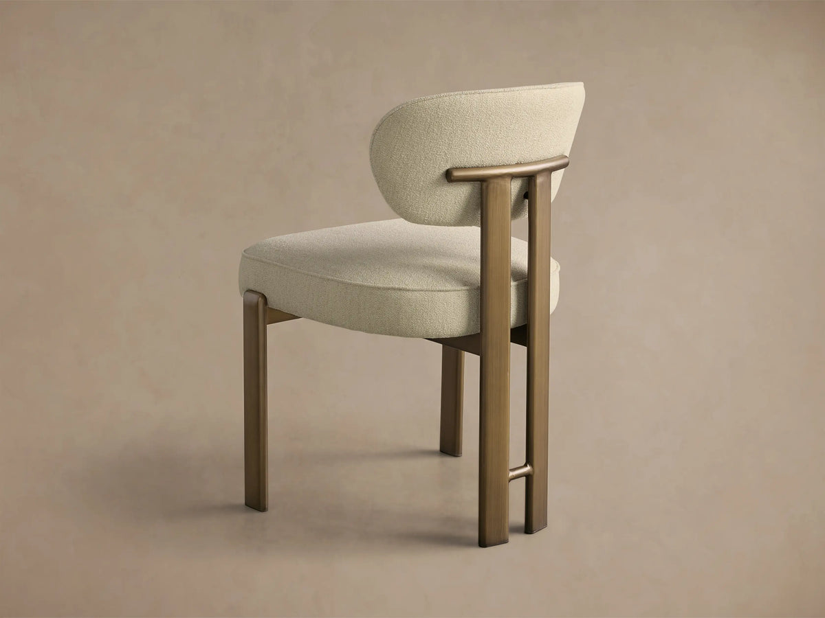 Close-up of the Cea Dining Side Chair with light beige textured upholstery and antique brass frame.