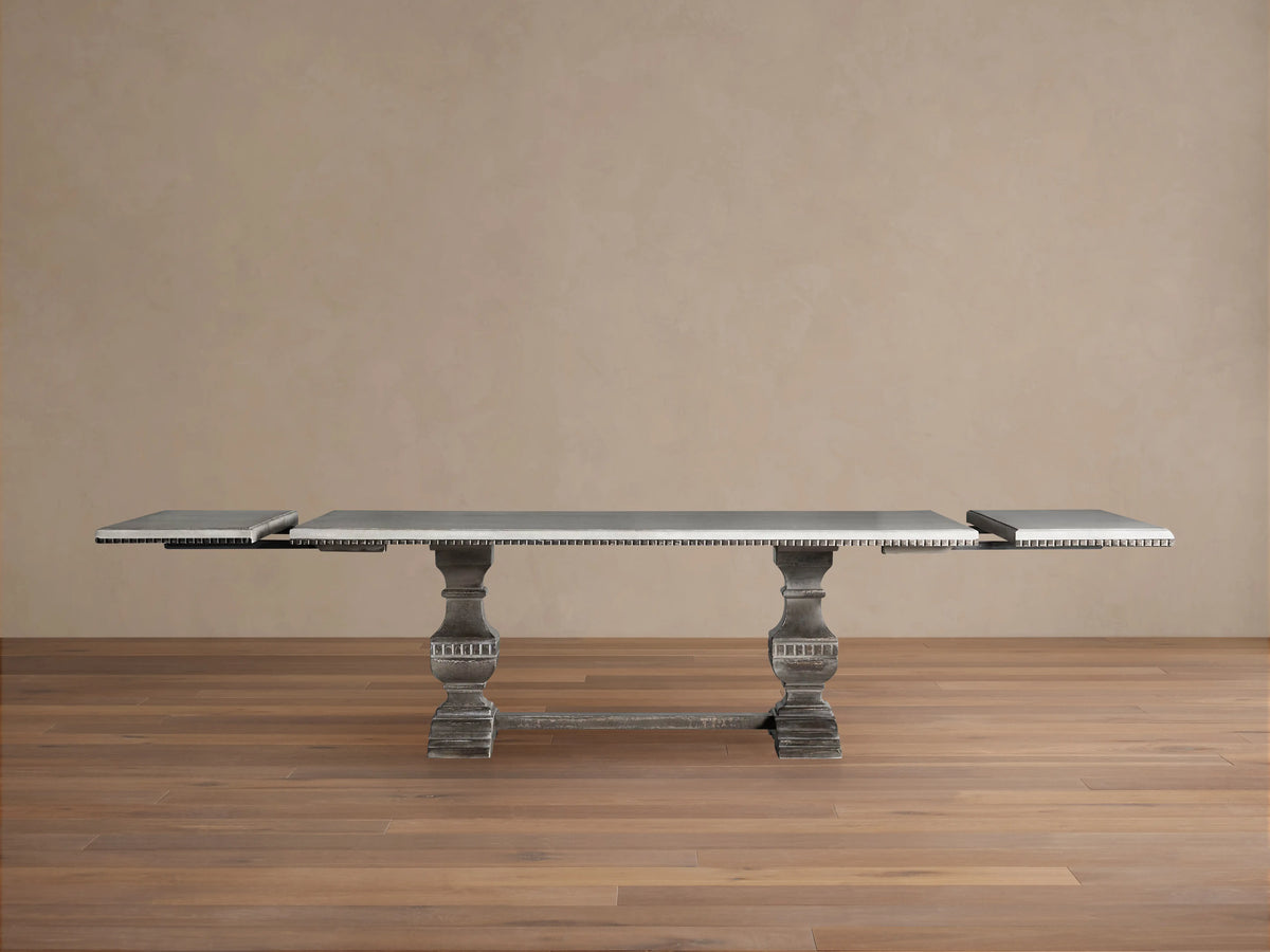 Cerea Amalfi Bell'Arte Dining Table: rectangular dark grey top with intricate patterned edge, two distressed grey pedestal legs.