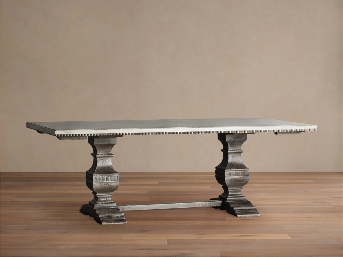 Cerea Amalfi Bell'Arte Dining Table with light gray top, dark distressed pedestal bases, and subtle hand-painted apron detail.