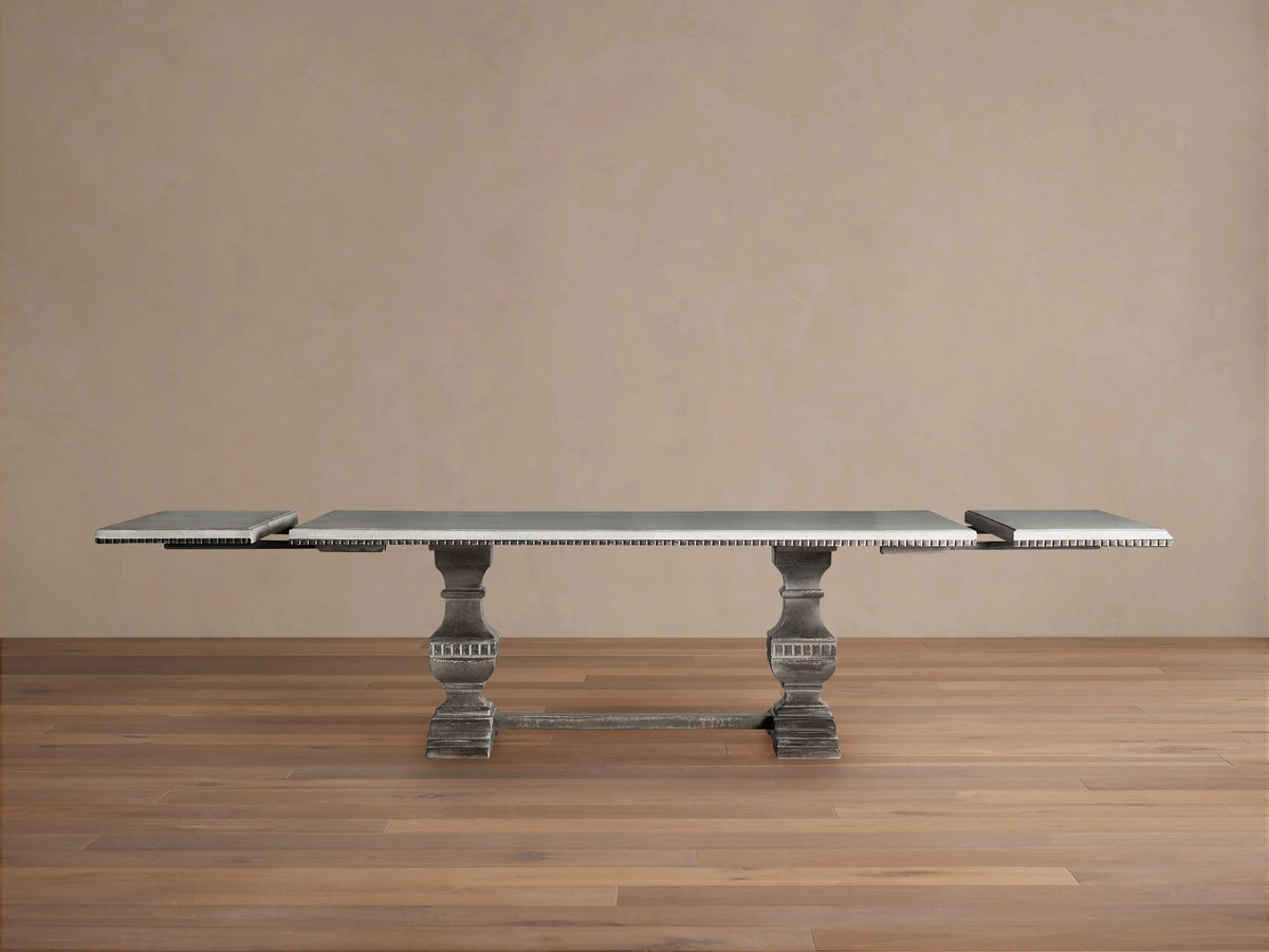 Cerea Amalfi Bell'Arte Dining Table with distressed dark grey pedestal base and light rectangular top with visible extensions.