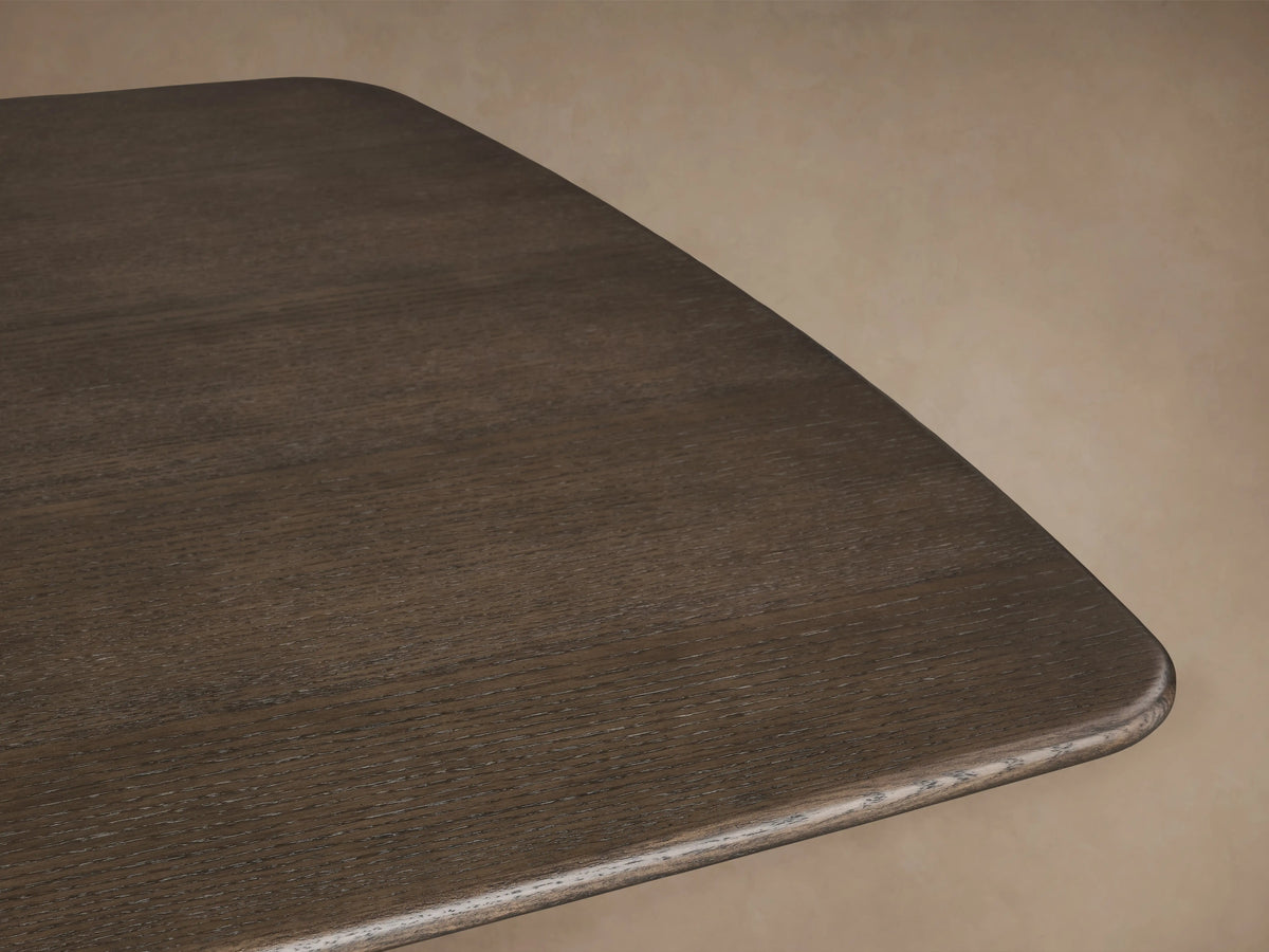 Saint Germain Wood Dining Table with dark oak rectangular top and brass-colored steel pedestal base on wooden floor.