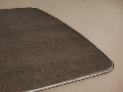 Saint Germain wood dining table in ebony finish with unique Rennes base on a wooden floor, against a beige wall.