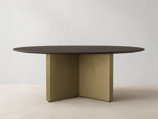 Round dining table with a solid oak chestnut finish top and a V-shaped antique brass steel base on a wooden floor.