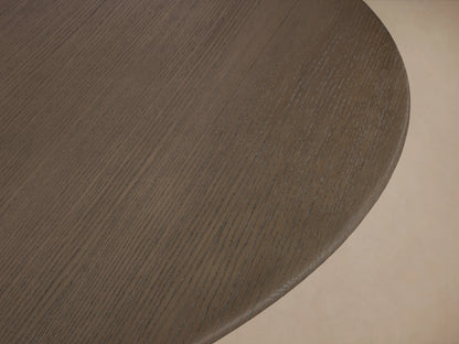 Round dining table with a dark wood top and an intersecting flat-base design finished in ebony, placed on a wooden floor.