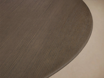 Round dining table with dark wood tabletop and black triangular base, set against a neutral background on wood flooring.