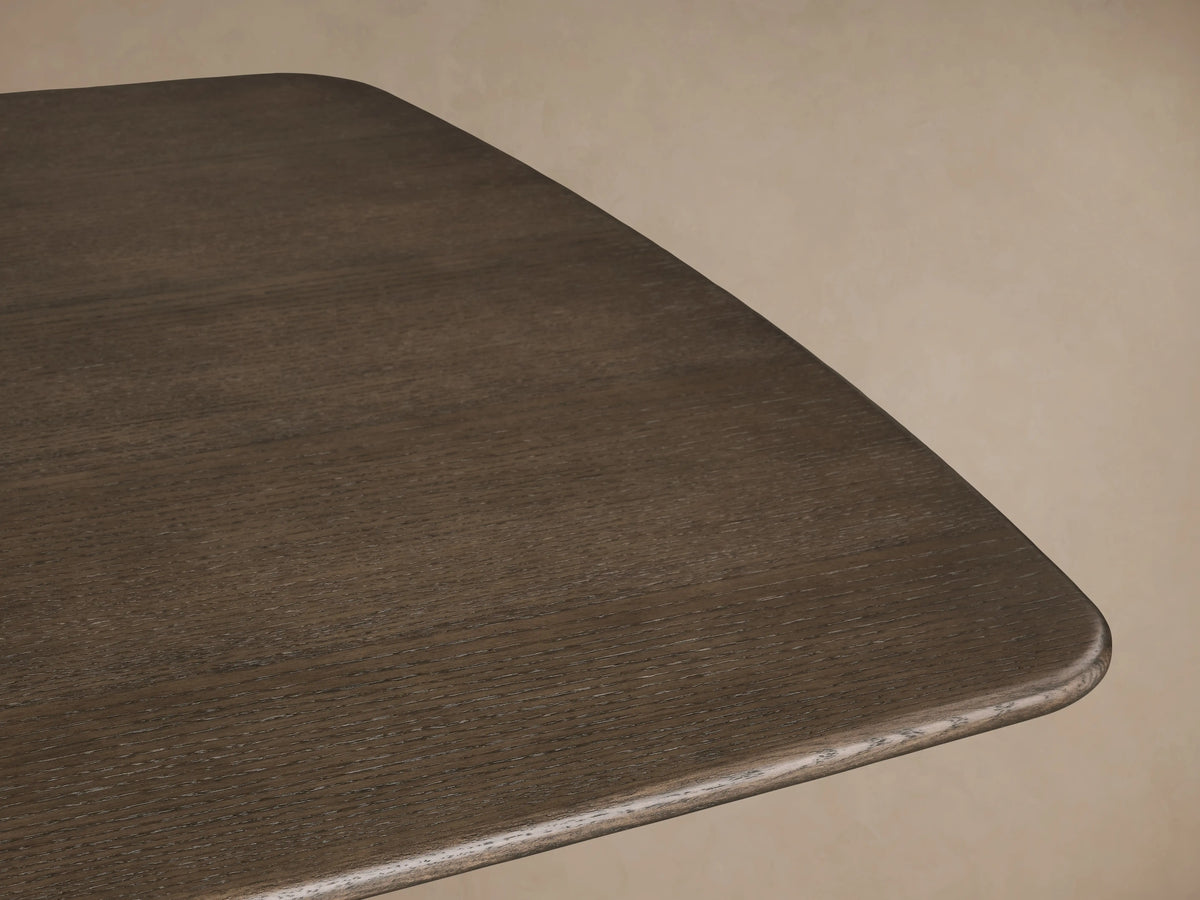 Corner view of Saint Germain Wood Dining Table with a dark wood finish, showcasing smooth, rounded edges and visible grain texture.