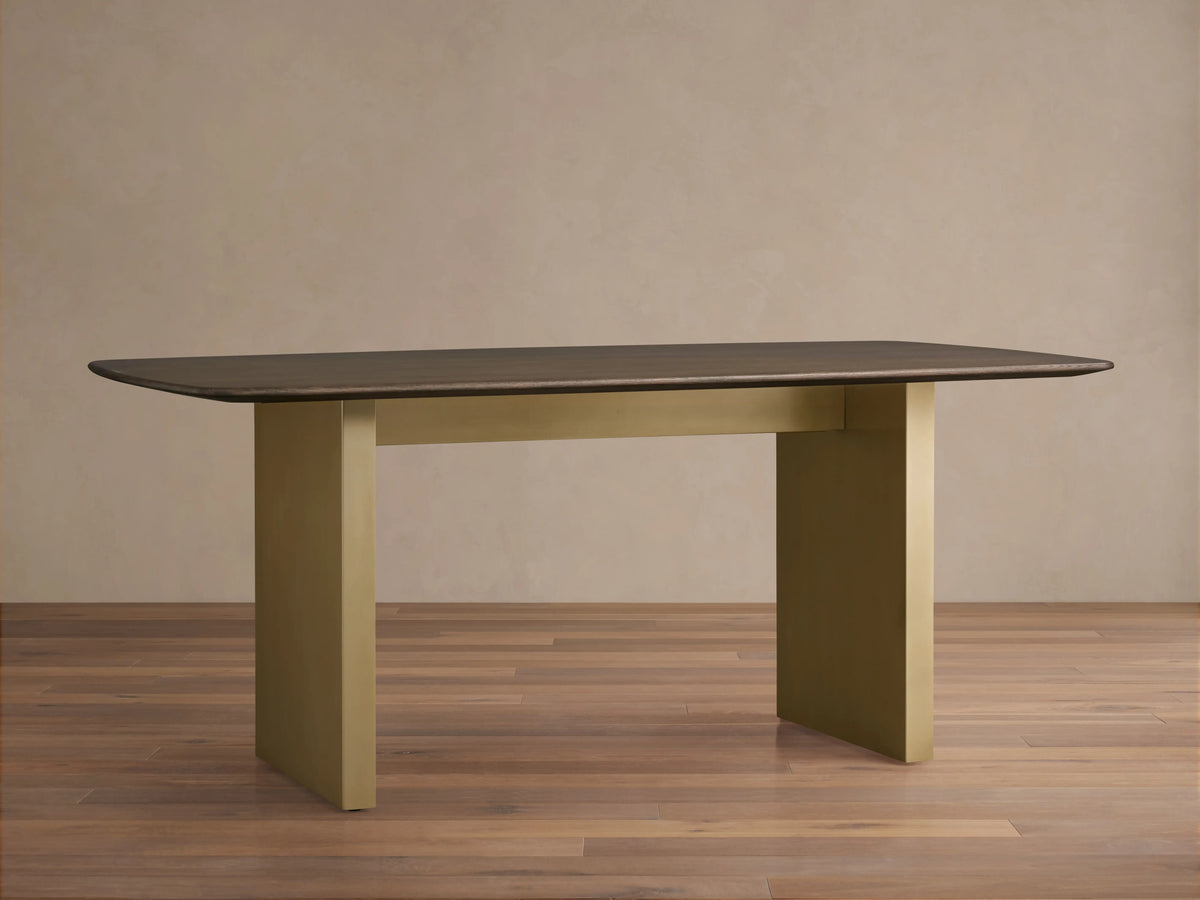 Saint Germain Wood Dining Table with an oak top and antique brass-finished steel base, on a hardwood floor, beige background.