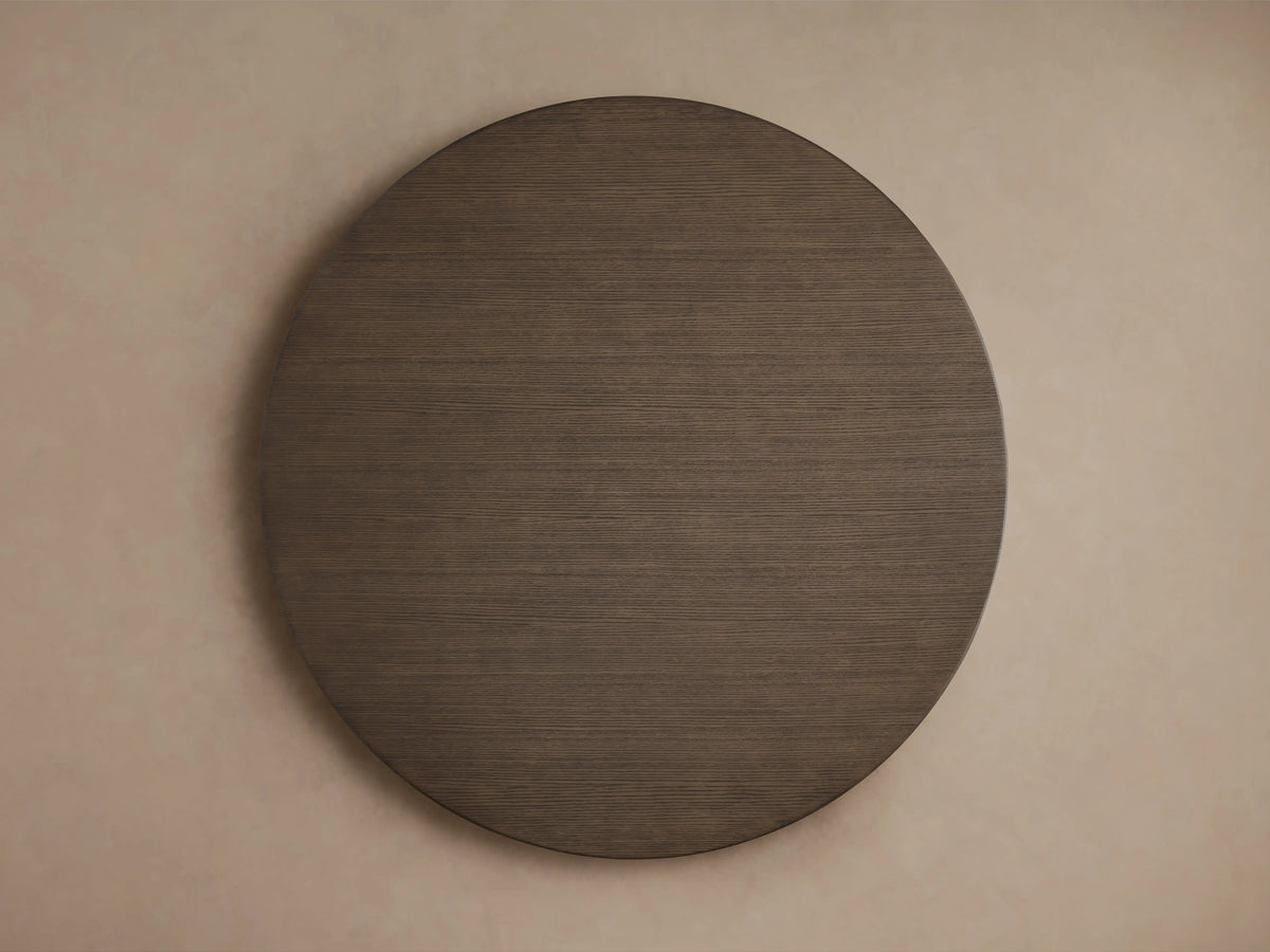 Saint Germain Round Wood Dining Table with a dark wooden top and a cross-shaped dark base on a wooden floor.