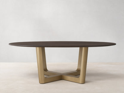 Saint Germain Round Wood Dining Table with a dark oak top on a brass-finished, cross-shaped Rennes base, set on wooden floor.