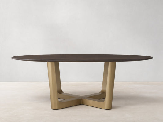 Saint Germain Round Wood Dining Table with a dark oak top on a brass-finished, cross-shaped Rennes base, set on wooden floor.
