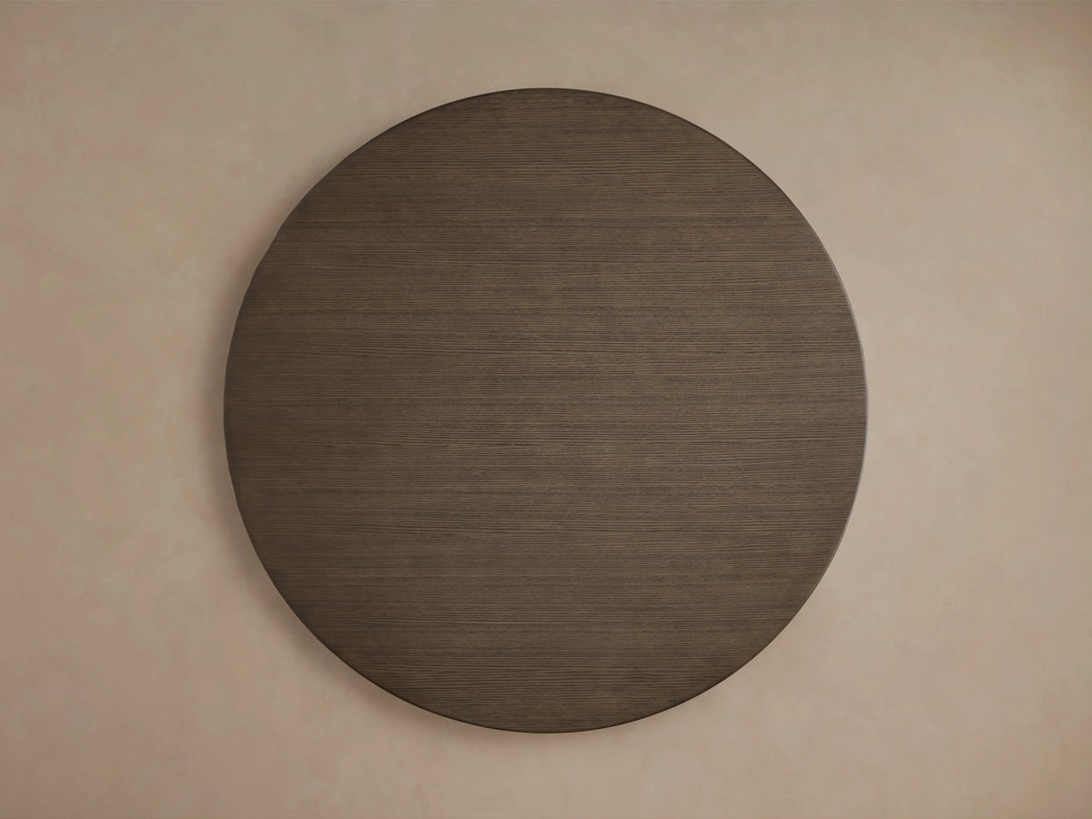 A detailed view of the Saint Germain Round Wood Dining Table's tabletop, showing the dark oak veneer with a smooth, rich chestnut finish.