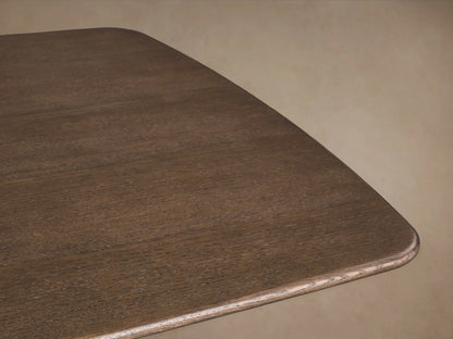 Close-up of a Saint Germain Dining Table corner with a smooth, rich Chestnut finish on solid oak, set against a neutral background.