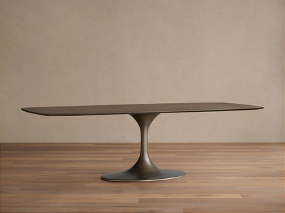 Saint Germain Wood Dining Table with an elongated oval oak tabletop in a dark finish, supported by a sleek, curved steel base.