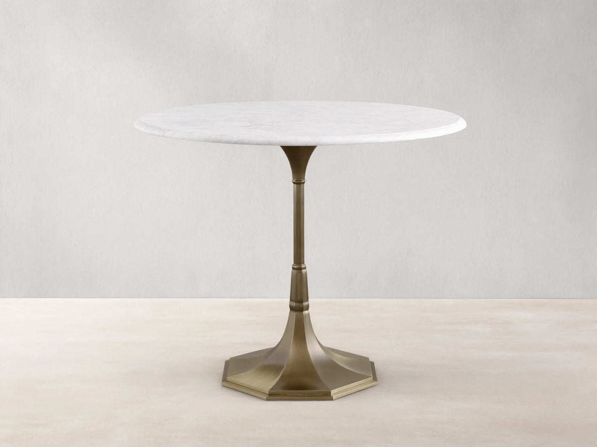Front view of the Clemence Bistro Table with a white Carrara marble top and a brass-toned tulip-style pedestal base.