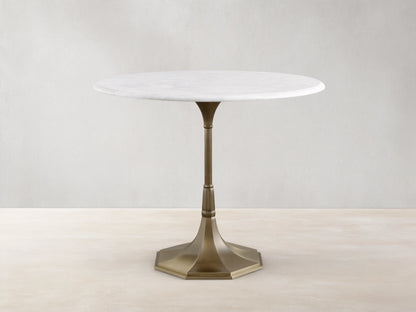 Front view of the Clemence Bistro Table with a white Carrara marble top and a brass-toned tulip-style pedestal base.