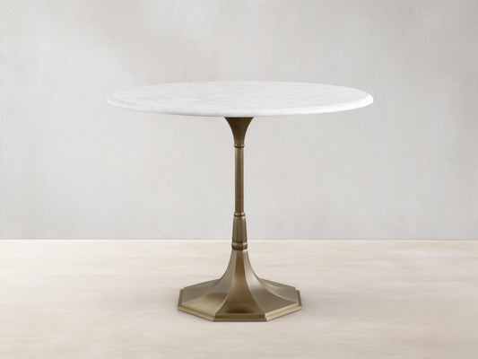 Front view of the Clemence Bistro Table with a white Carrara marble top and a brass-toned tulip-style pedestal base.