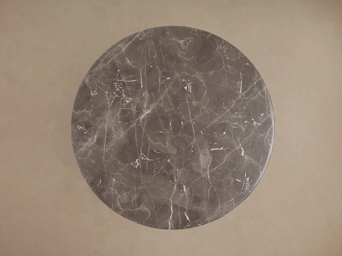Overhead view of the round, dark gray marble top of the Clemence Bistro Table, showing intricate white veining patterns.