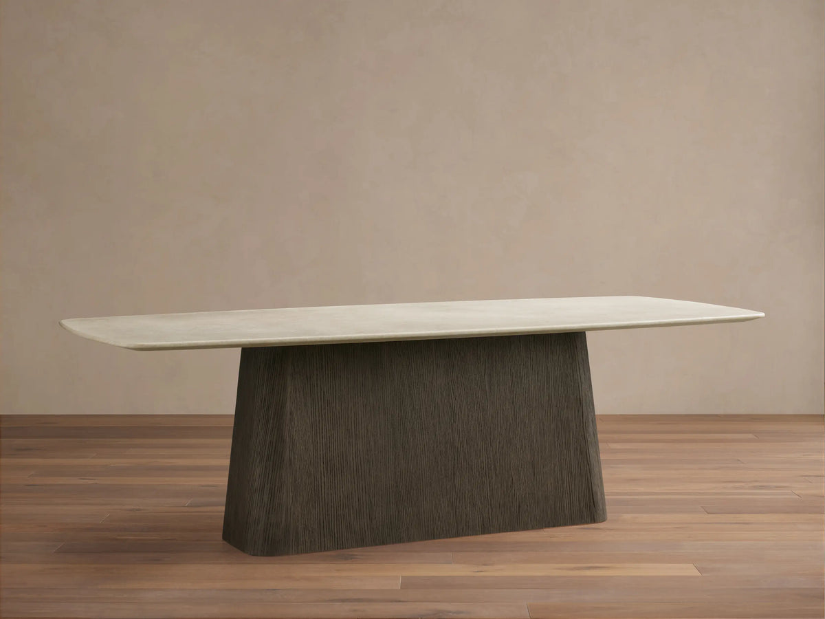 Saint Germain dining table: light cream stone top, rounded, with dark brown textured wood Toulouse base on a wood floor.