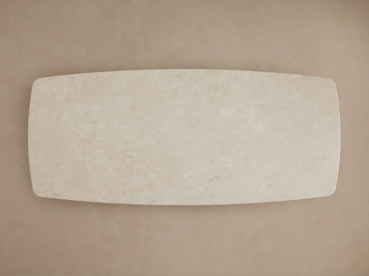 Close-up of Saint Germain Stone Dining Table's cream marble top, showing subtle veining and a smooth, rounded corner.