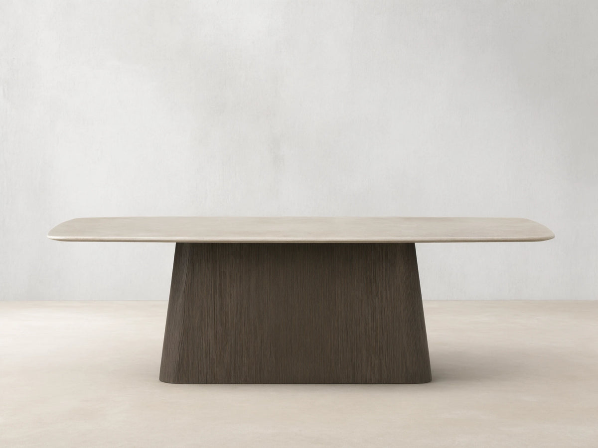 Saint Germain dining table: light cream stone top, rounded, with dark brown textured wood Toulouse base on a wood floor.