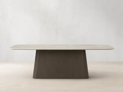 Saint Germain dining table: light cream stone top, rounded, with dark brown textured wood Toulouse base on a wood floor.