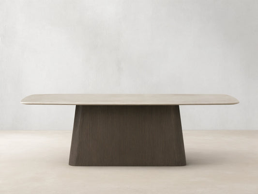 Saint Germain dining table: light cream stone top, rounded, with dark brown textured wood Toulouse base on a wood floor.