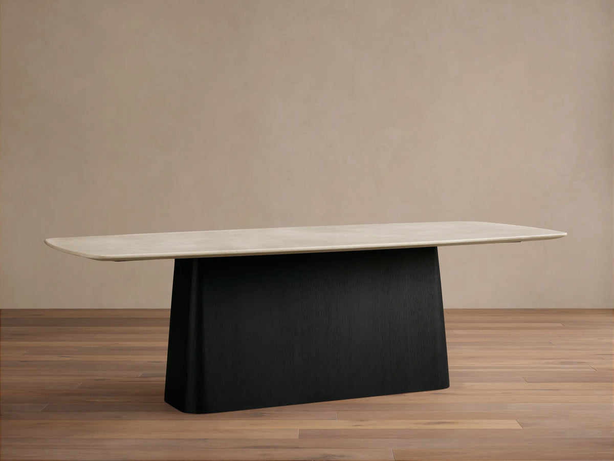Saint Germain dining table with a rectangular cream stone top and a solid black Toulouse base, on a wooden floor.