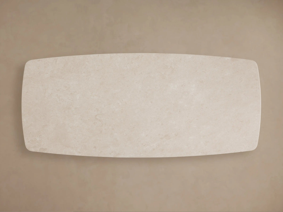 Close-up of the creamy Saint Germain Stone Dining Table's rounded corner, showing natural veining on its surface.