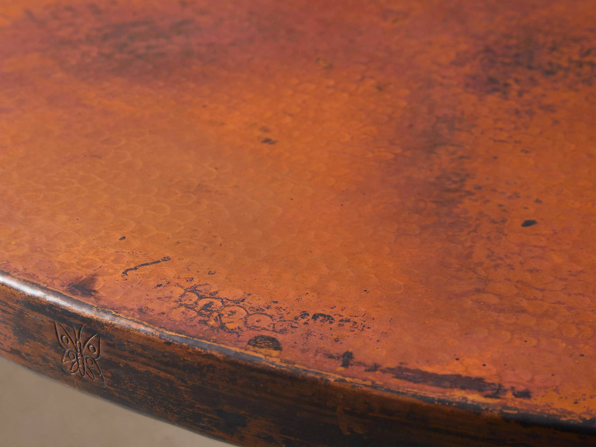 Recycled Metal Bistro Table with a round, rustic copper-toned top and a sturdy black Wade pedestal base on wood floor.