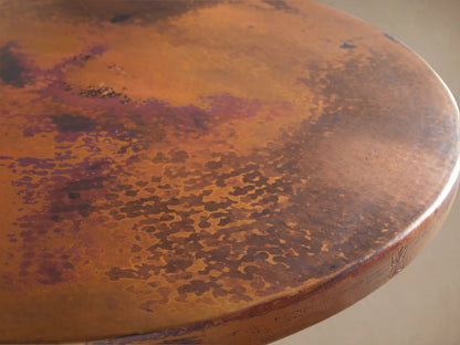Recycled Metal Bar Table with Wade Base featuring a round wooden tabletop and black iron pedestal base on a wooden floor.