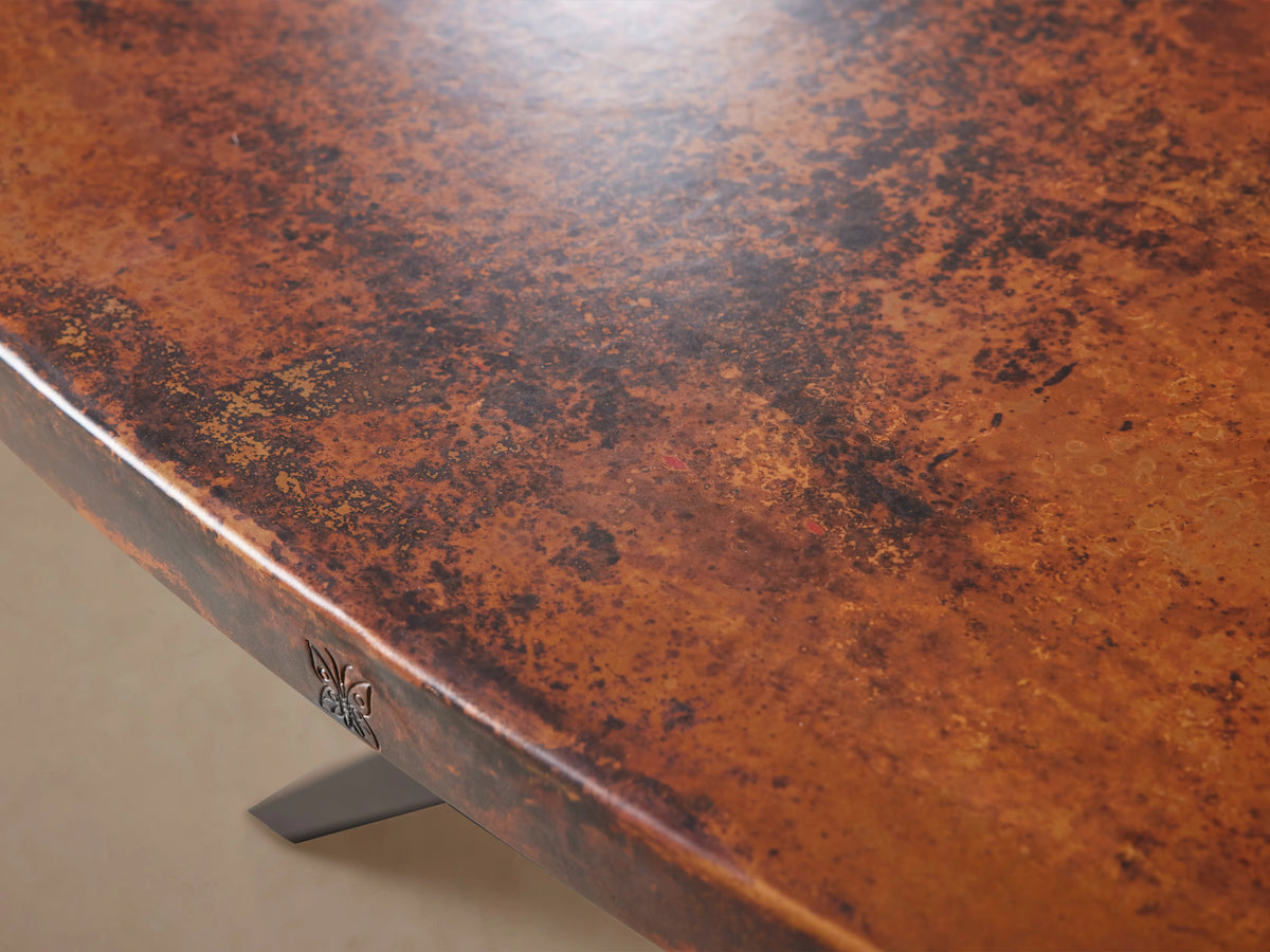 Oval Recycled Metal Dining Table with hammered copper-toned top & varied patina, on a flat black iron Vertex base.
