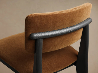 Close-up back view of the Corrado Dining Side Chair, showing brown upholstered backrest and dark ash wood frame with a textured bar.