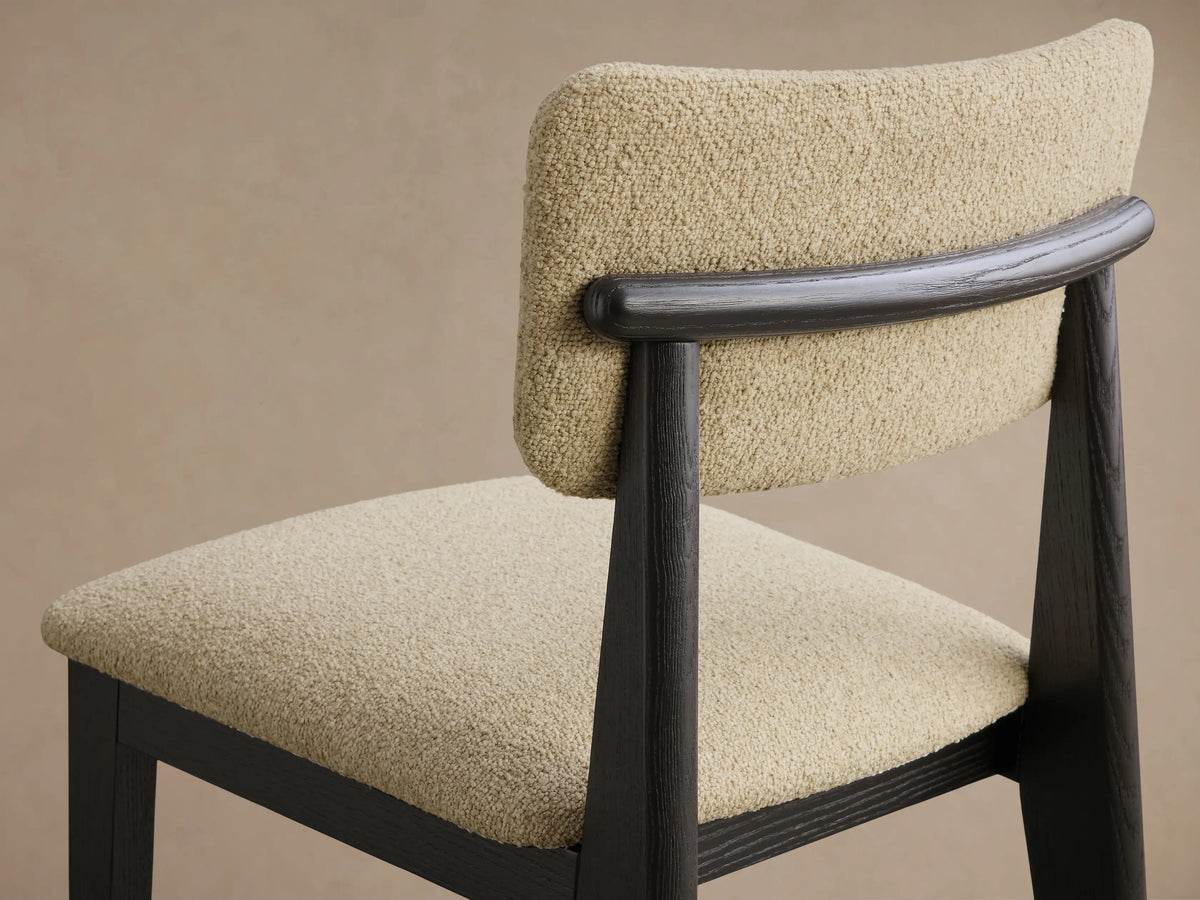 Front view of a dark ash wood Corrado Dining Side Chair with a textured beige upholstered seat and back.