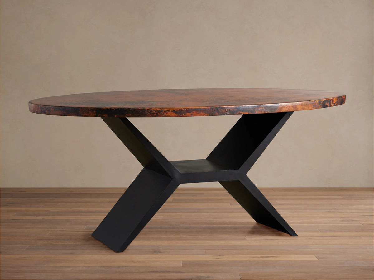 Recycled Metal Dining Table with an oval, reddish-brown variegated copper tabletop and a black, angular Vertex base.
