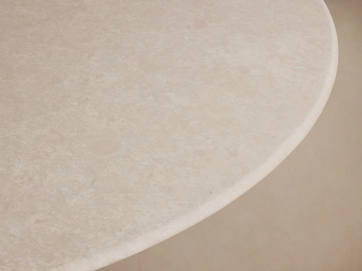 Round edge of Saint Germain dining table in cream marble, showing smooth surface with natural veining and subtle texture.