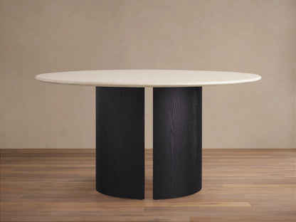 Round dining table with a smooth, light stone top and dark wood base. Set on wood flooring against a neutral wall.