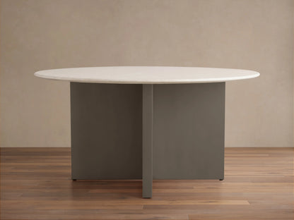 Round dining table with a light stone top, featuring a minimalist base with intersecting dark panels, on a wooden floor.