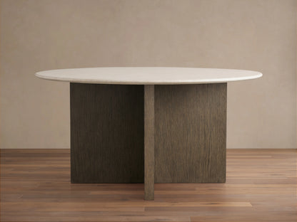 Round dining table with a smooth Carrara marble top. The wood base is a cross design in a chestnut finish, set on a wooden floor.