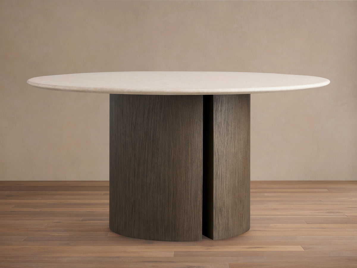 Round dining table with cream marble top and Dauphine base. Base has two curved oak veneer panels in a neutral tone.