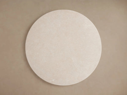Round stone tabletop in light cream color, showing subtle natural variations and veining, with smooth, curved edge.