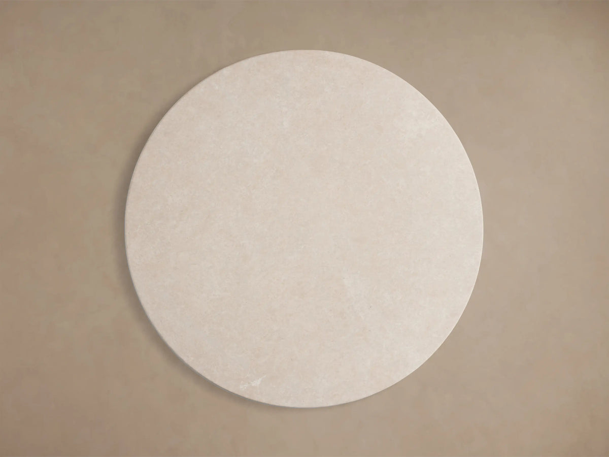 Close-up of the beige honed stone top of the Saint Germain Round Stone Dining Table with Launette Base.