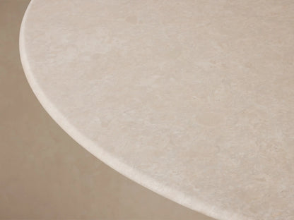 Front view of the Saint Germain Round Stone Dining Table with Launette Base, featuring a light stone round top and a dark bronze hourglass-shaped steel base.