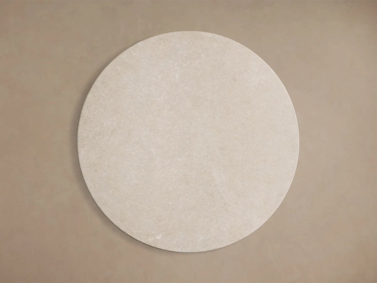 Close-up of the light beige honed stone tabletop of the Saint Germain Round Stone Dining Table with Launette Base.